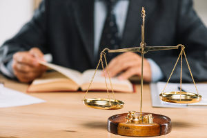 A lawyer studies a law book, with the scales of justice in the foreground,