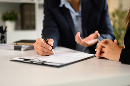 Two businesspeople in suits finalizing an important business deal at a modern office desk.