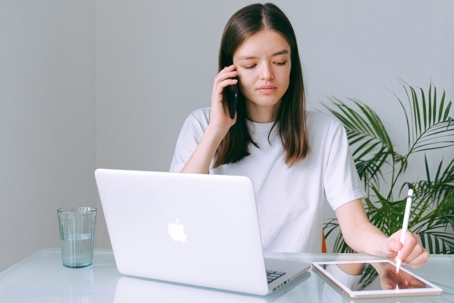 A woman works at a desk with a laptop and tablet.