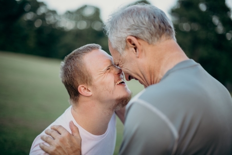 Close-up of a heartwarming moment between a man with Down syndrome and an older man.